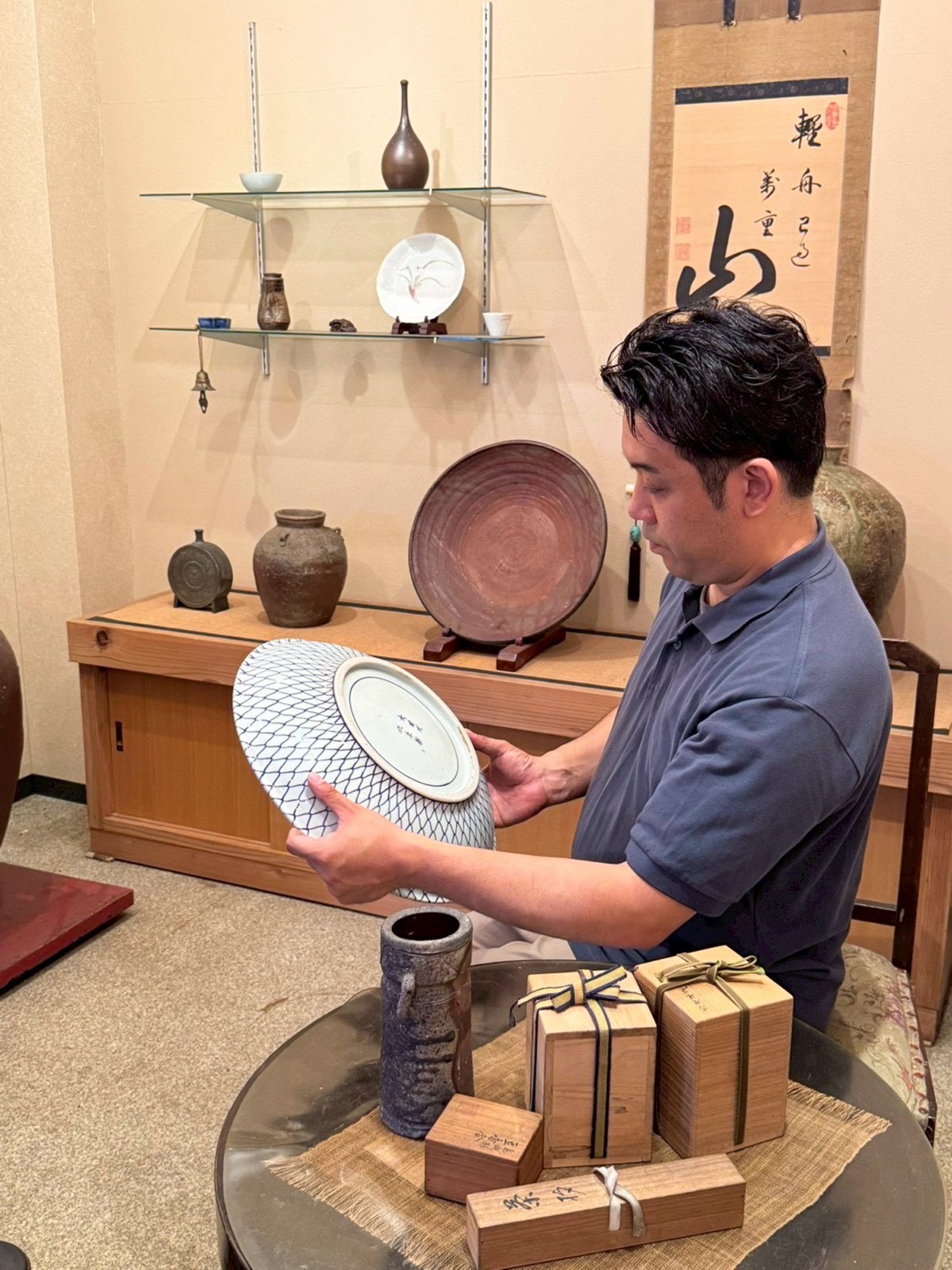 陳列棚の並ぶ店内で大皿を鑑定する様子